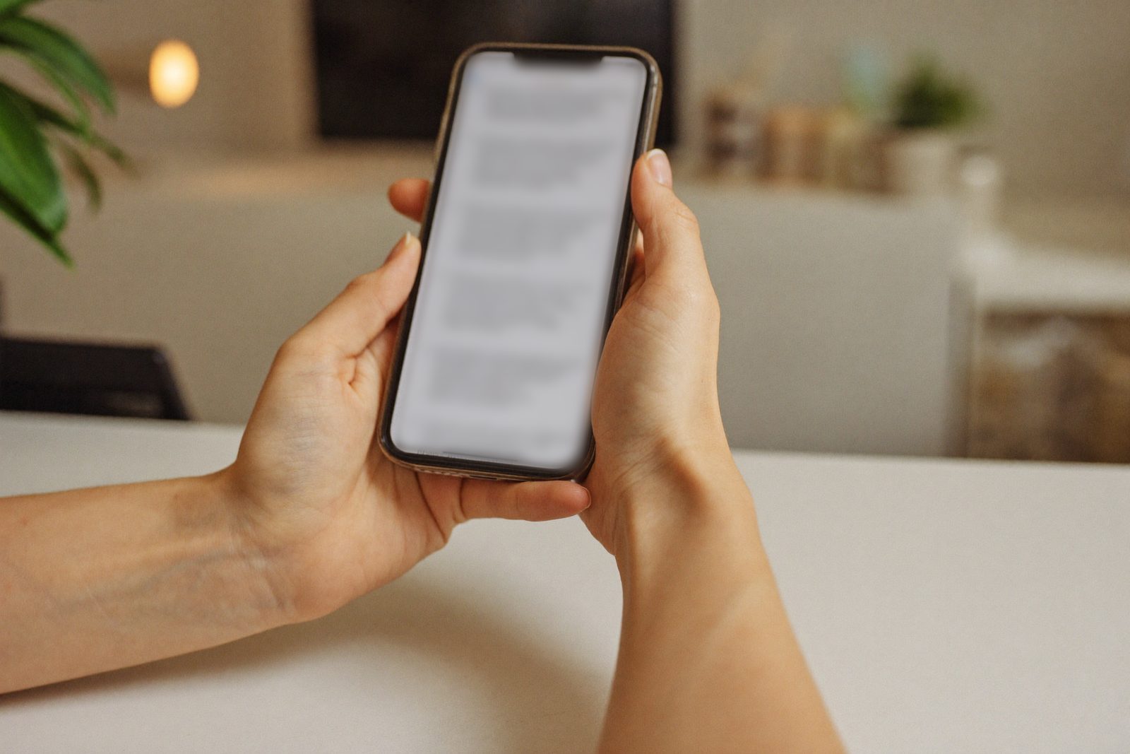 Mãos segurando um celular com uma lista de conversas, tela desfocada